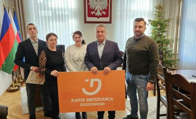 A group of entrepreneurs and Mayor Dariusz Kucharski hold a banner with the inscription Dzierżoniów Resident Card.