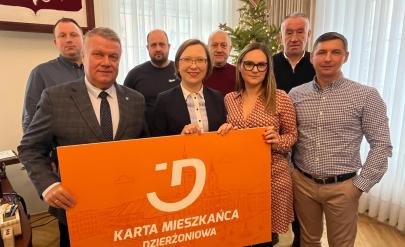 A group of entrepreneurs and Mayor Dariusz Kucharski are holding a banner with the inscription “Dzierżoniów Resident Card.”