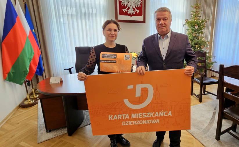 Dwie osoby trzymają pomarańczowy baner - Kartę Mieszkańca Dzierżoniowa