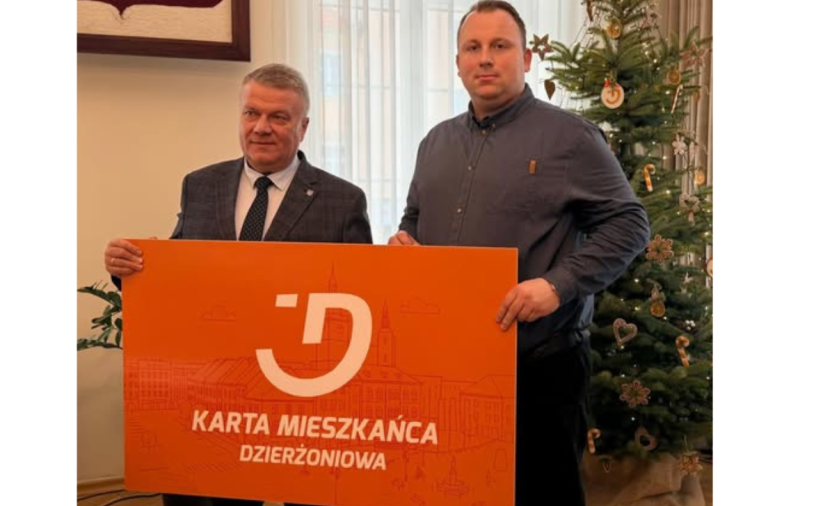 Dwie osoby trzymają pomarańczowy baner - Kartę Mieszkańca Dzierżoniowa