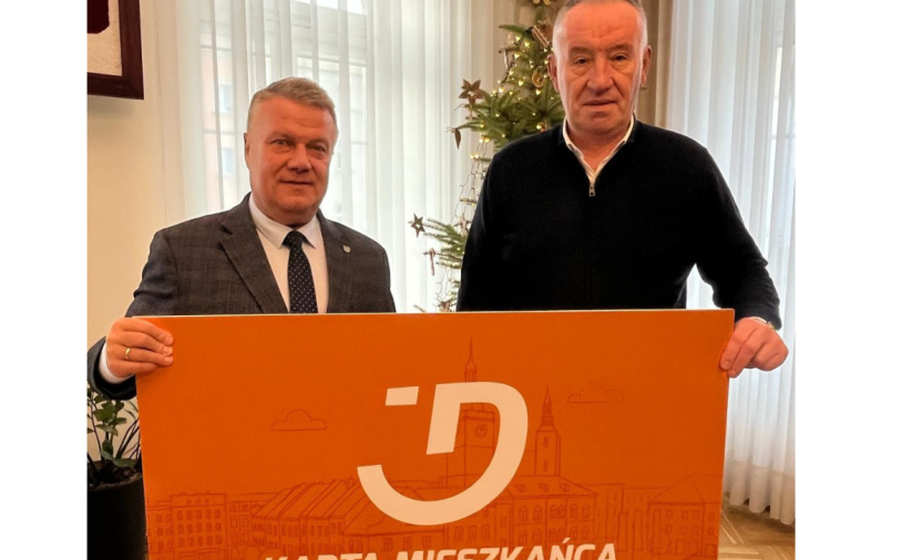 Dwie osoby trzymają pomarańczowy baner - Kartę Mieszkańca Dzierżoniowa
