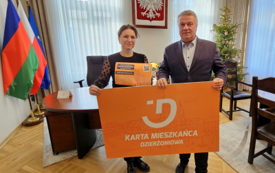 Dwie osoby trzymają pomarańczowy baner - Kartę Mieszkańca Dzierżoniowa