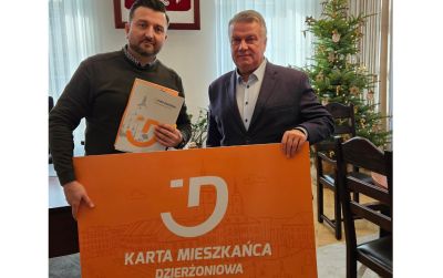 Dwie osoby trzymają pomarańczowy baner - Kartę Mieszkańca Dzierżoniowa