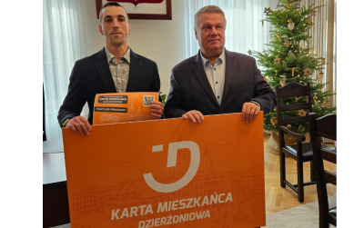 Dwie osoby trzymają pomarańczowy baner - Kartę Mieszkańca Dzi