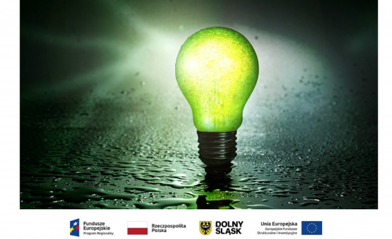 Zielona, święcąca żarówka na ciemnym tle. Pod grafiką loga Uni Europejskiej, flaga Polski.