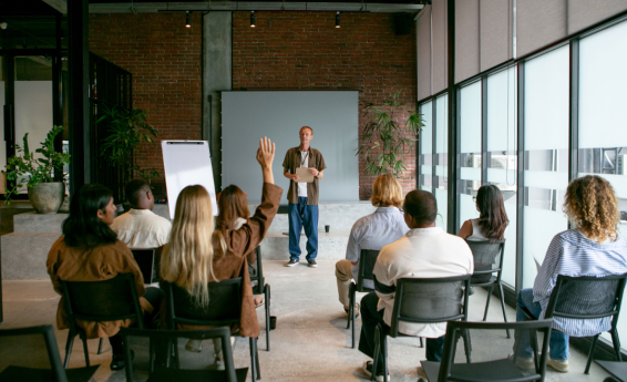 ludzie siedzą w sali wykładowej, na wprost prowadzący